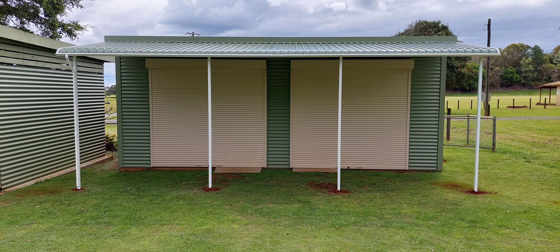 A green, metal shed with a wide, open porch — Budget Screens & Awnings in South Lismore, NSW