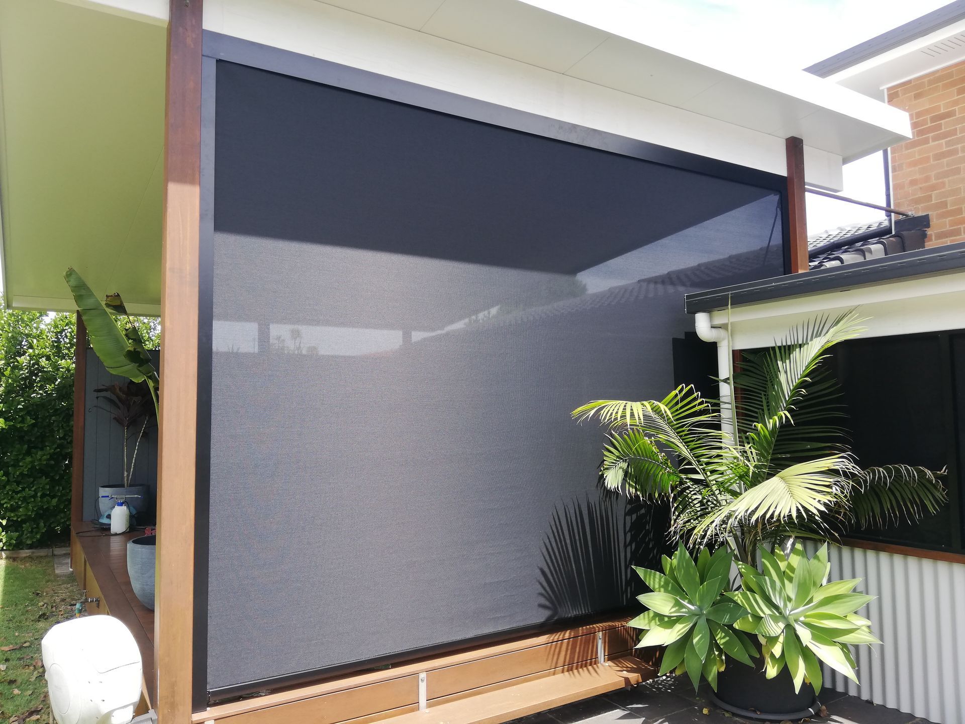 A black outdoor privacy screen installed on a wooden patio — Budget Screens & Awnings in South Lismore, NSW