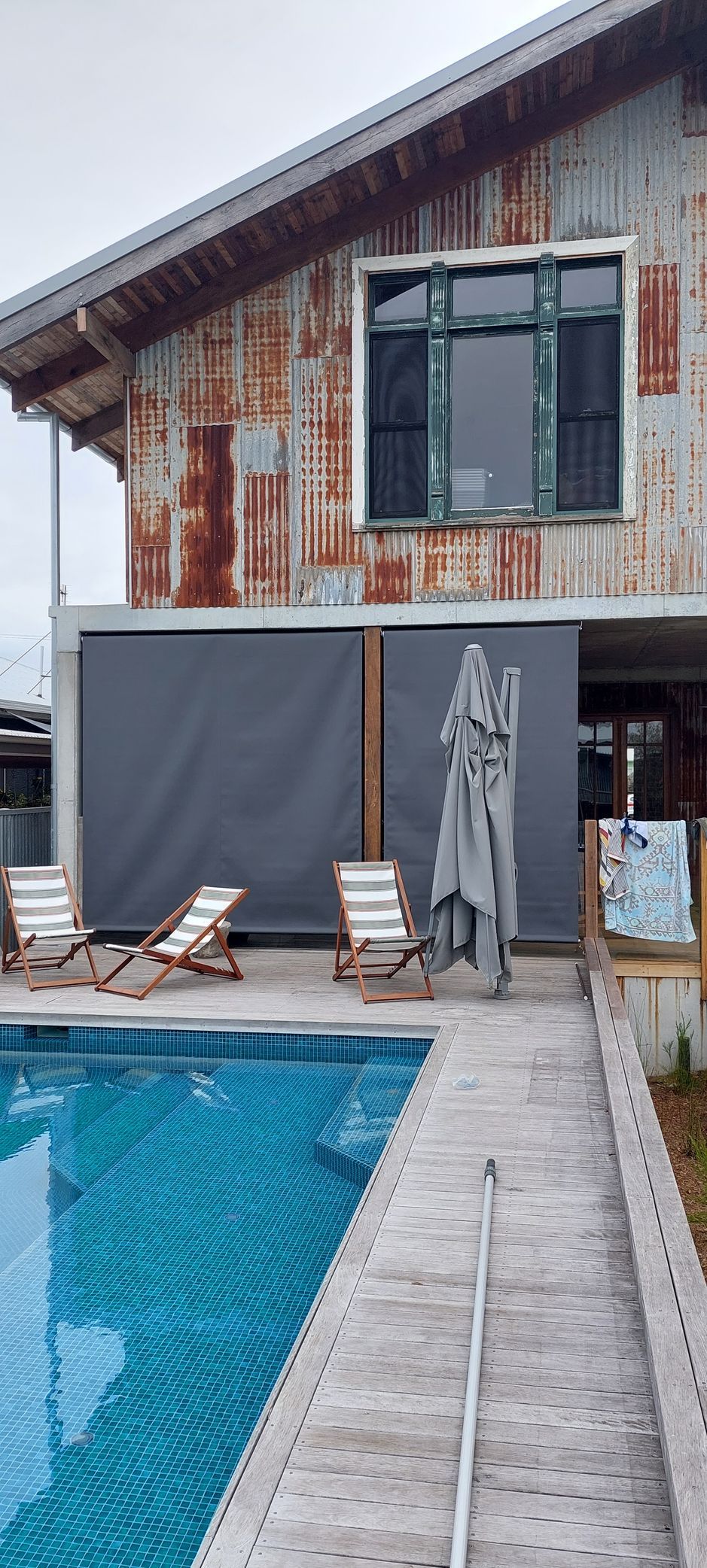 A rustic building with corrugated metal siding and grey privacy screens — Budget Screens & Awnings in South Lismore, NSW