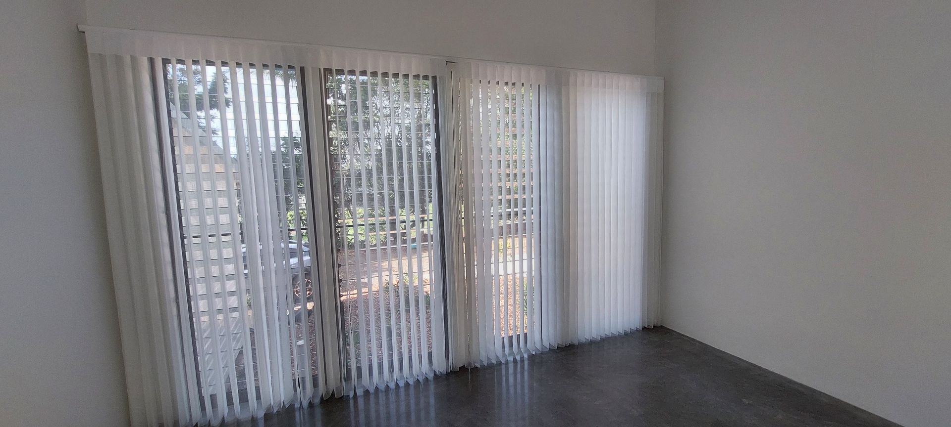Floor-to-ceiling white vertical blinds cover a glass door — Budget Screens & Awnings in South Lismore, NSW
