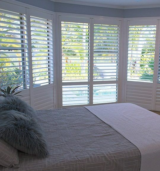 A Bedroom With a Bed and Shutters on the Windows — Budget Screens & Awnings in South Lismore, NSW