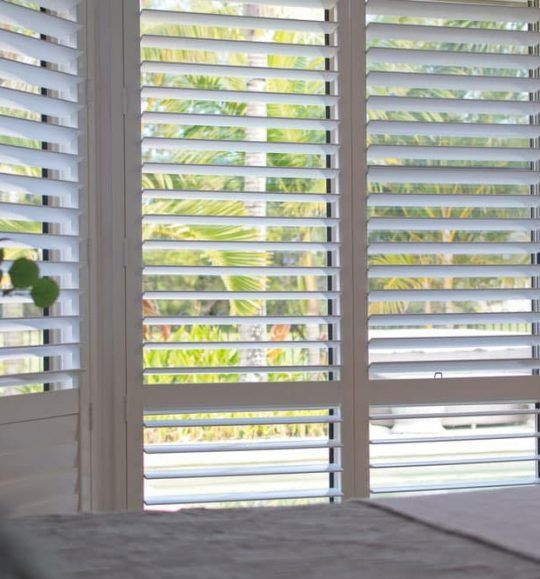 A Window With Shutters on It and a Table in Front of It — Budget Screens & Awnings in South Lismore, NSW
