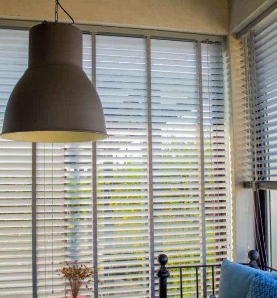 There is a Lamp Hanging From the Ceiling in Front of a Window With Blinds — Budget Screens & Awnings in South Lismore, NSW