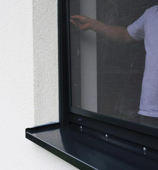 A Man is Standing in Front of a Window With a Screen — Budget Screens & Awnings in South Lismore, NSW