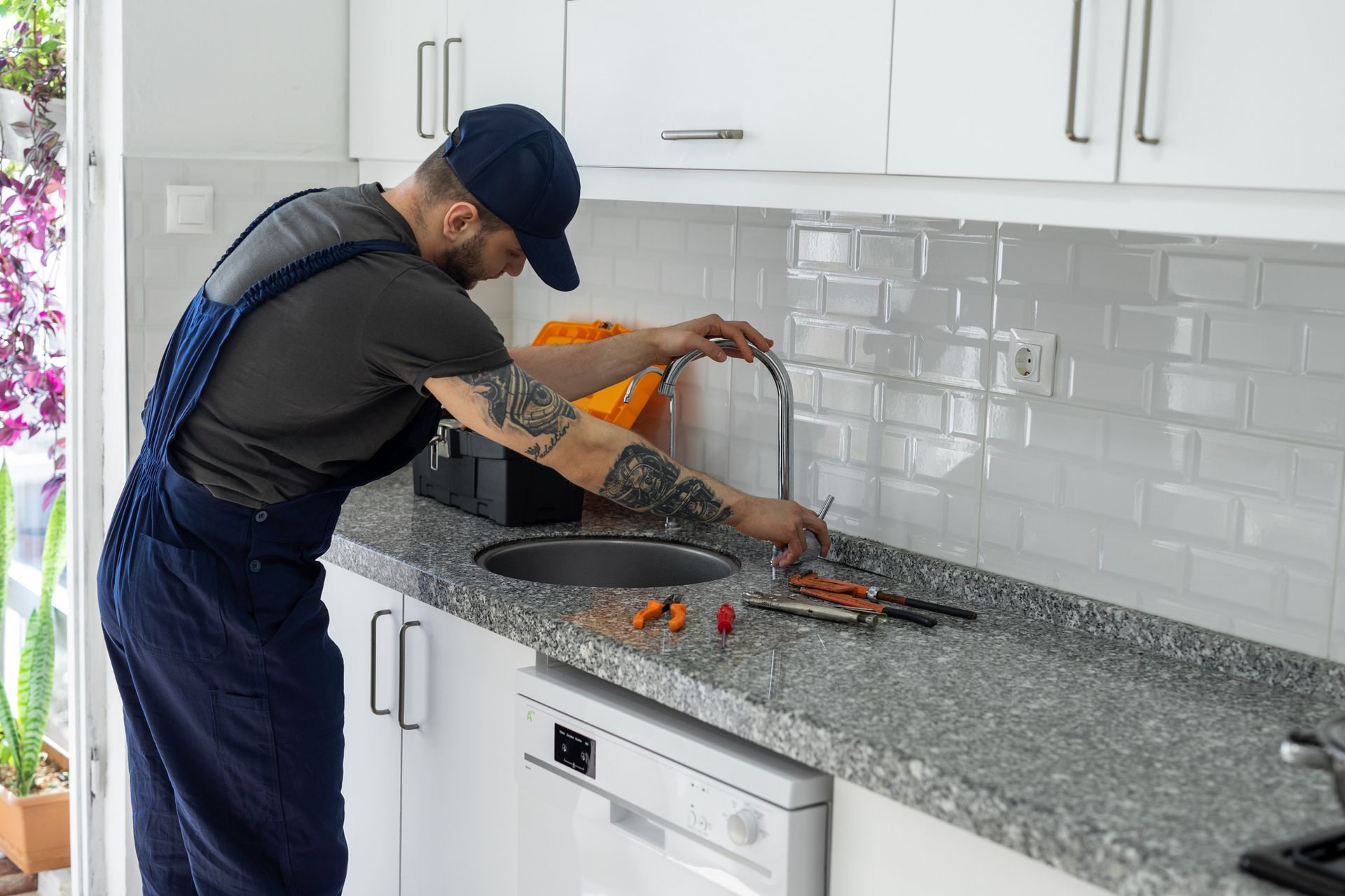 A man is fixing a faucet in a kitchen.