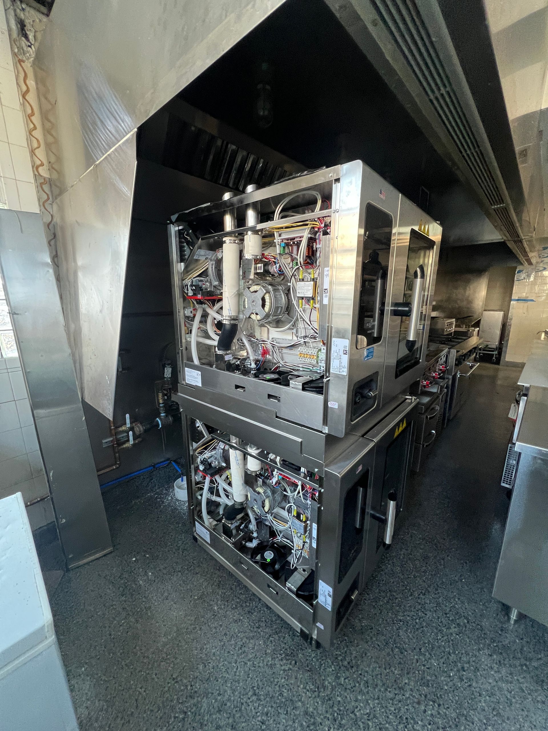 Industrial machine with exposed wiring inside a metal enclosure in a narrow corridor