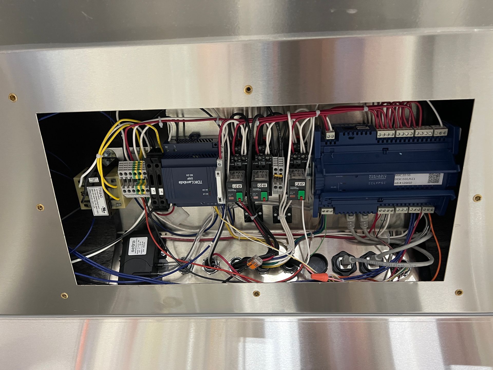Open electrical control panel with circuit boards, wiring, and modules inside a metal cabinet.