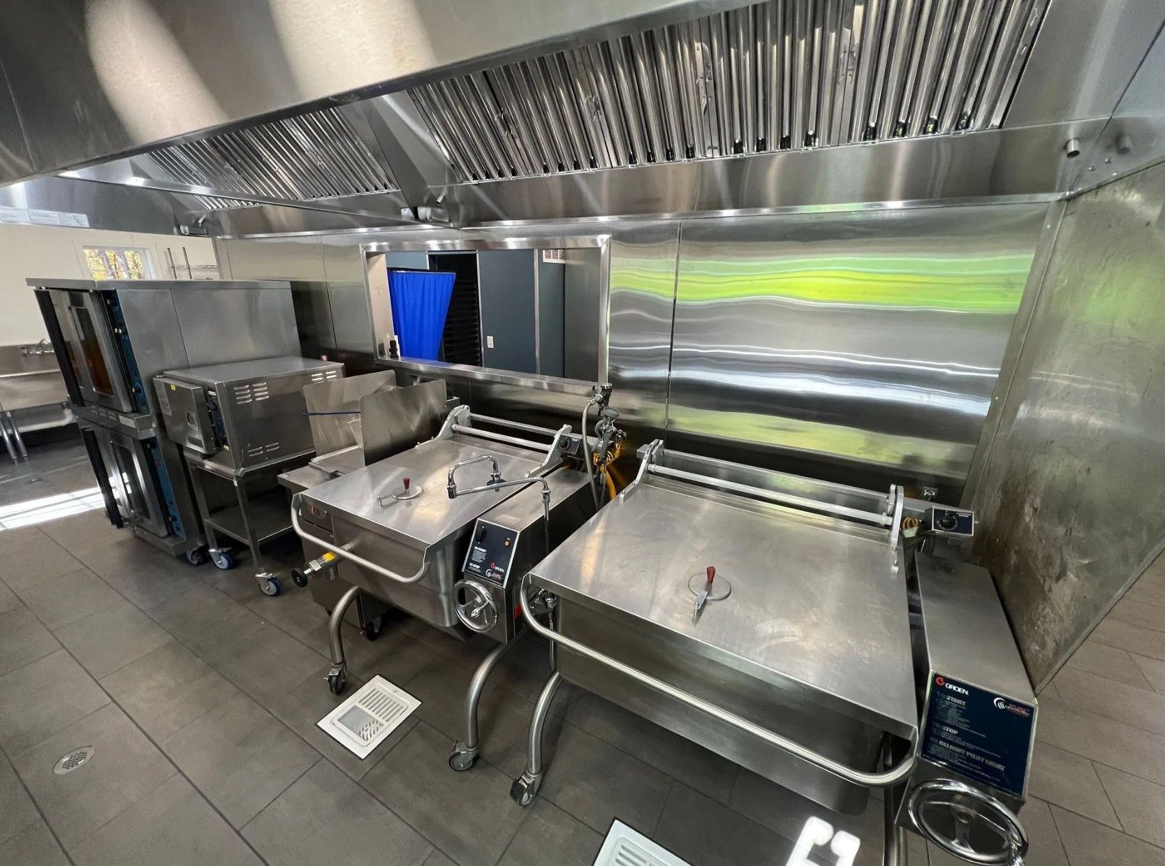 Commercial kitchen with stainless steel equipment and vent hood.