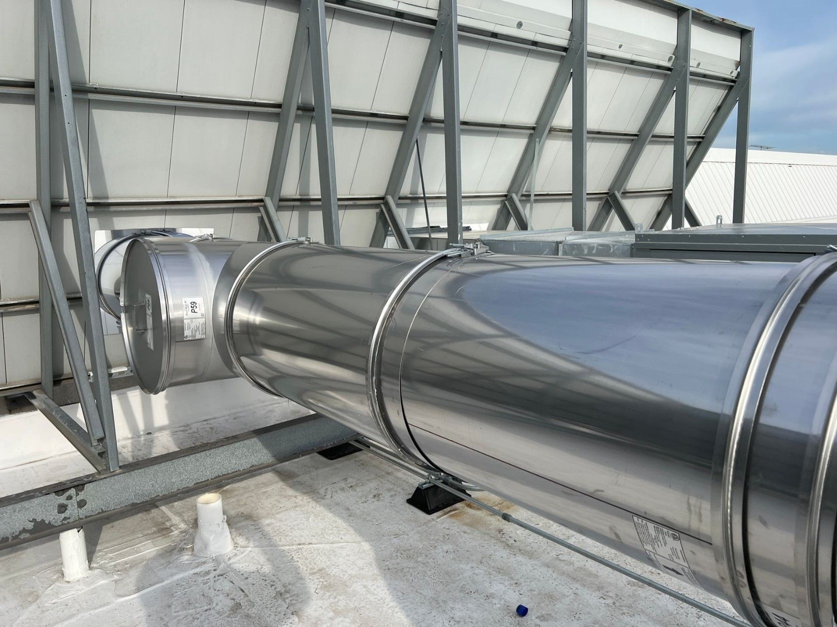 Stainless steel HVAC ducting on a rooftop, supported by a metal frame.
