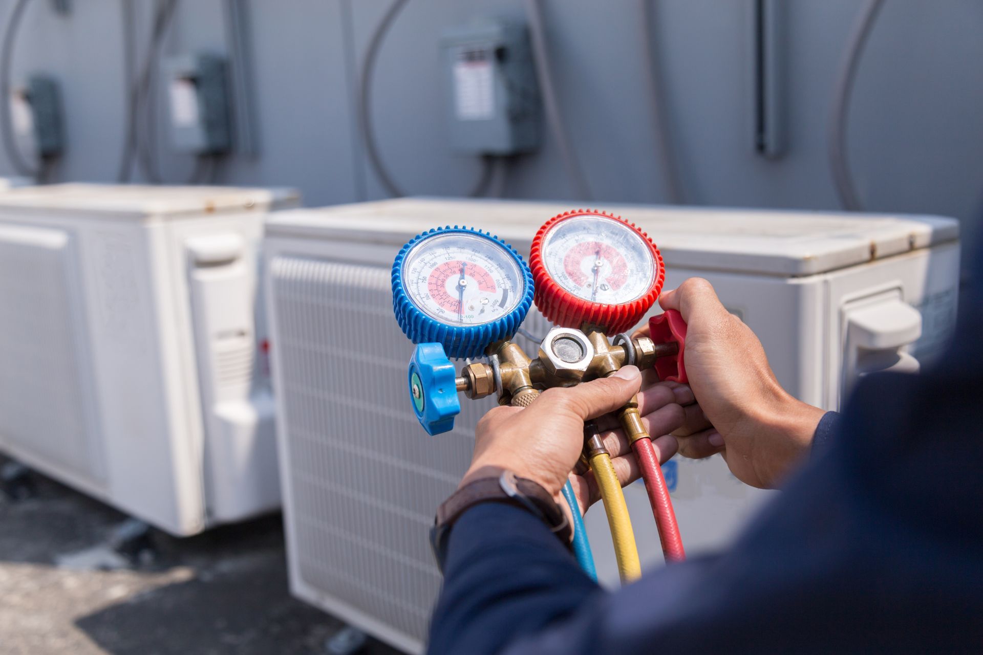 HVAC technician using gauges on an outdoor air conditioning unit to check pressure.