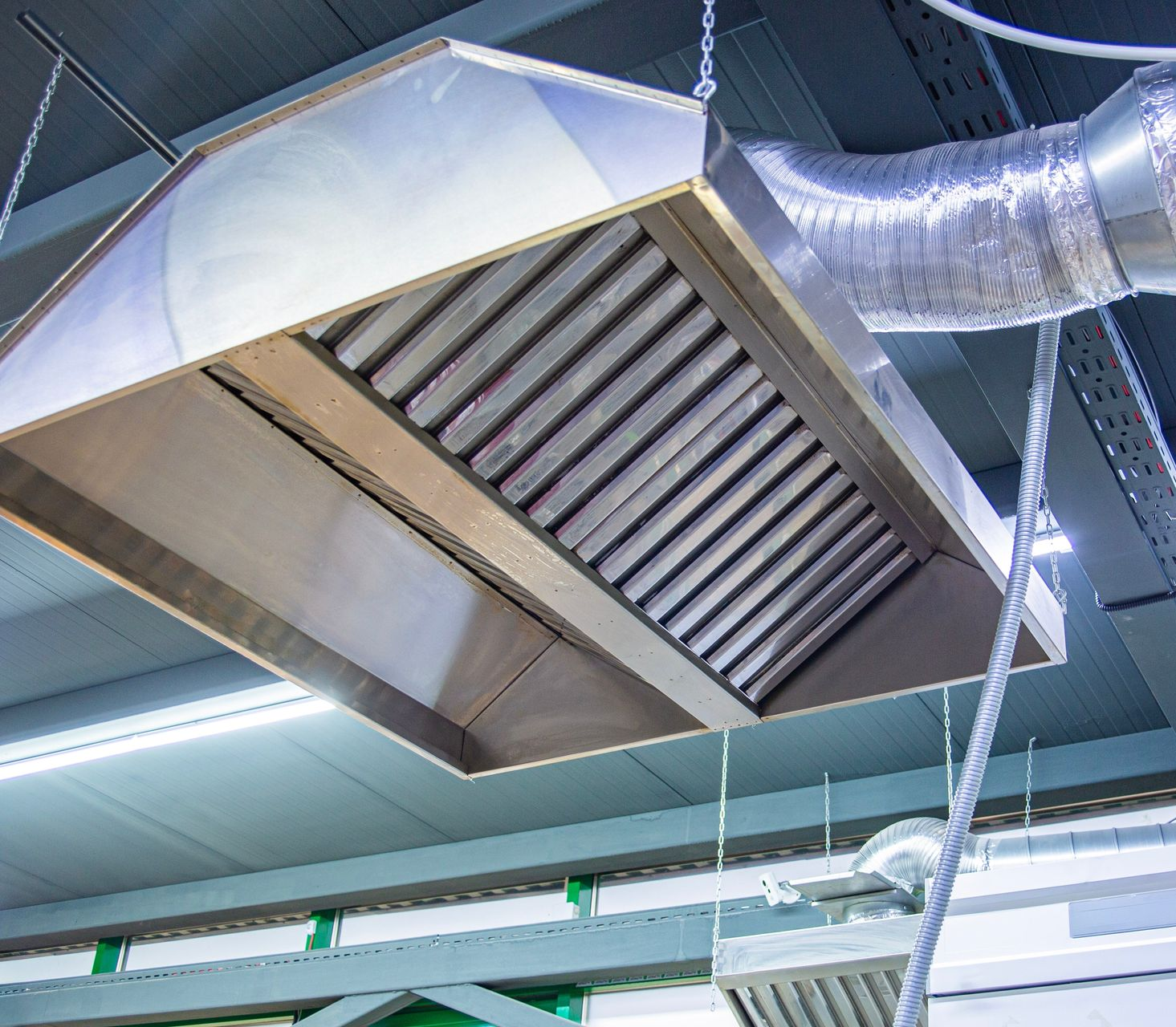 Stainless steel commercial kitchen range hood with filter grates viewed from below