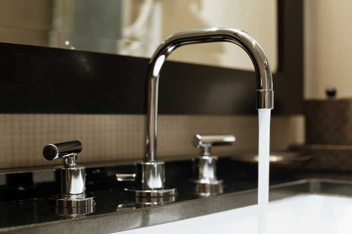 Chrome faucet with water running into a sink.