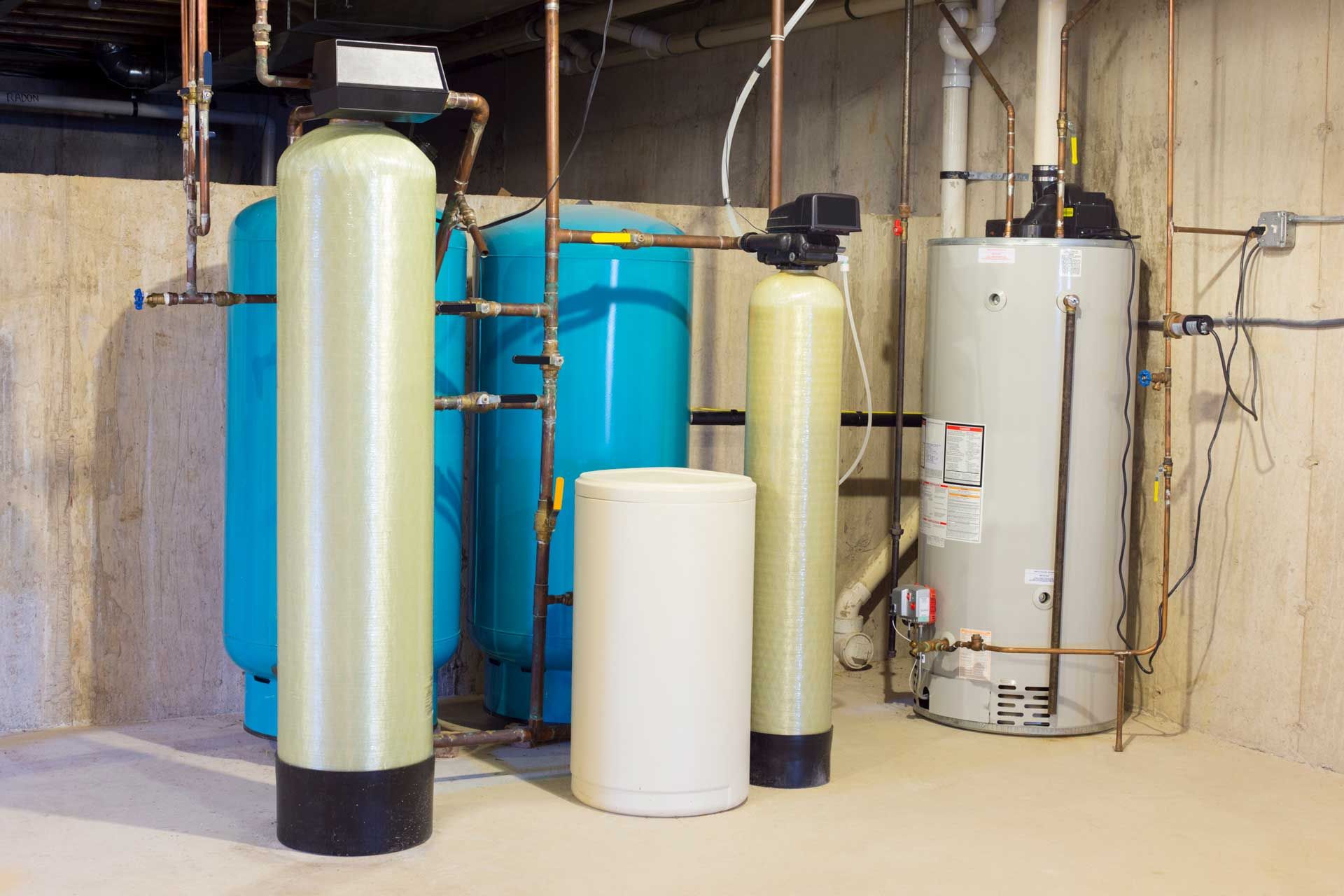 Water treatment and heating system in a basement: tanks, pipes, and a water heater.