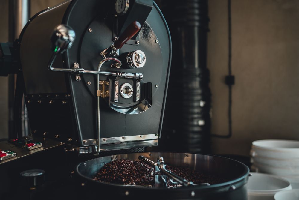 Black Coffee Roaster with Freshly Roasted Beans in A Tray — Projected Contracting Electrical Services In Port Douglas, QLD