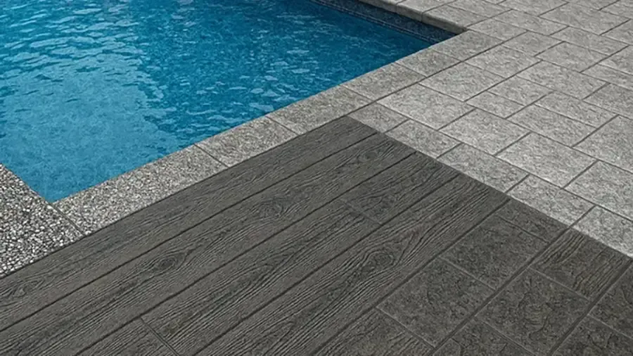 Blue pool water beside gray stone and dark textured walkway tiles