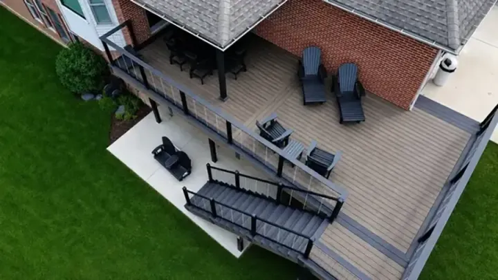 Aerial view of a brick house backyard deck with patio furniture and green lawn