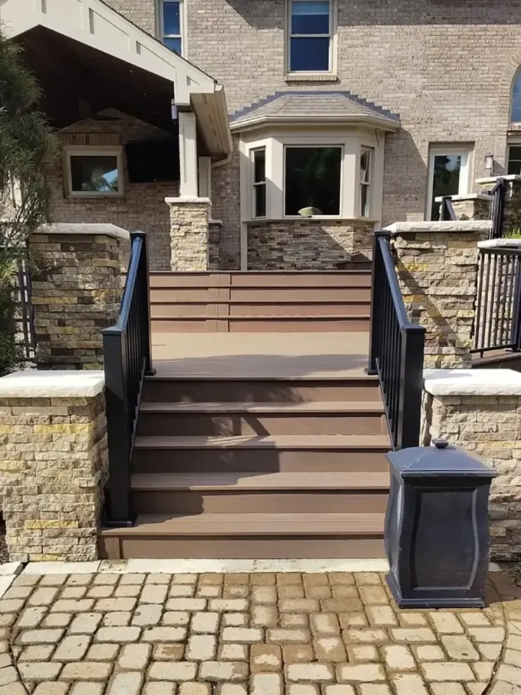 Stone front steps with black railings leading to a brick house entrance.