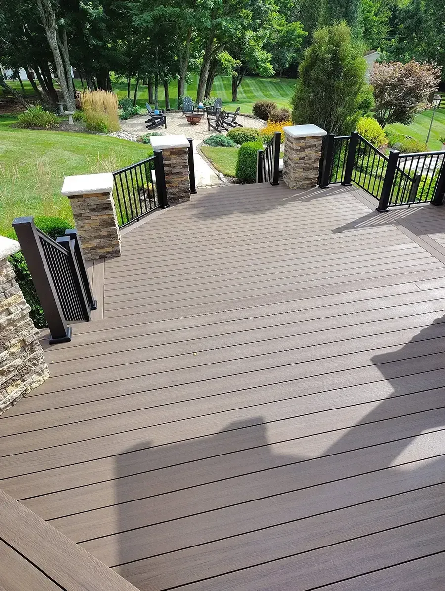 Curved wooden deck steps leading to a lush garden path with stone posts and black railings