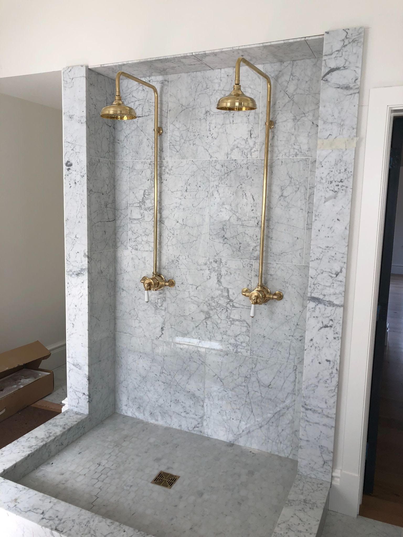 Hand adjusting a wrench on a wall-mounted shower faucet in a tiled bathroom