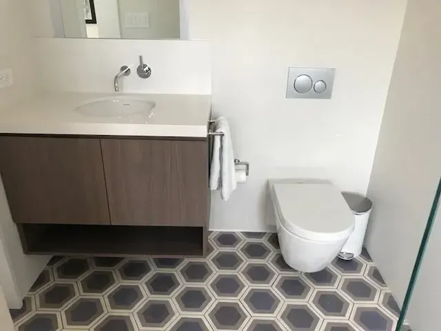 Modern bathroom with vanity sink, wall toilet, and hexagon tile floor