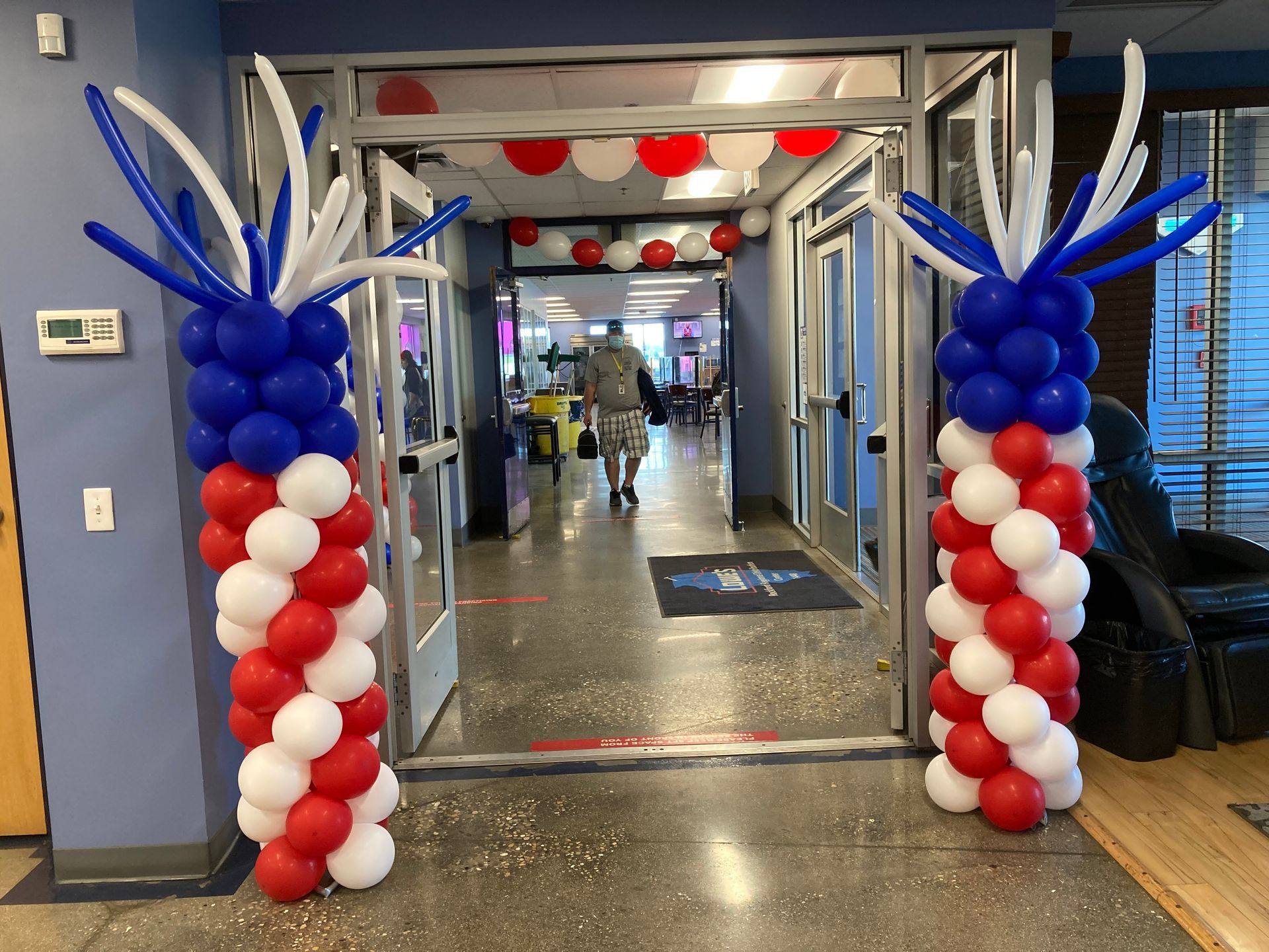 Red white and blue balloons are lined up in a hallway
