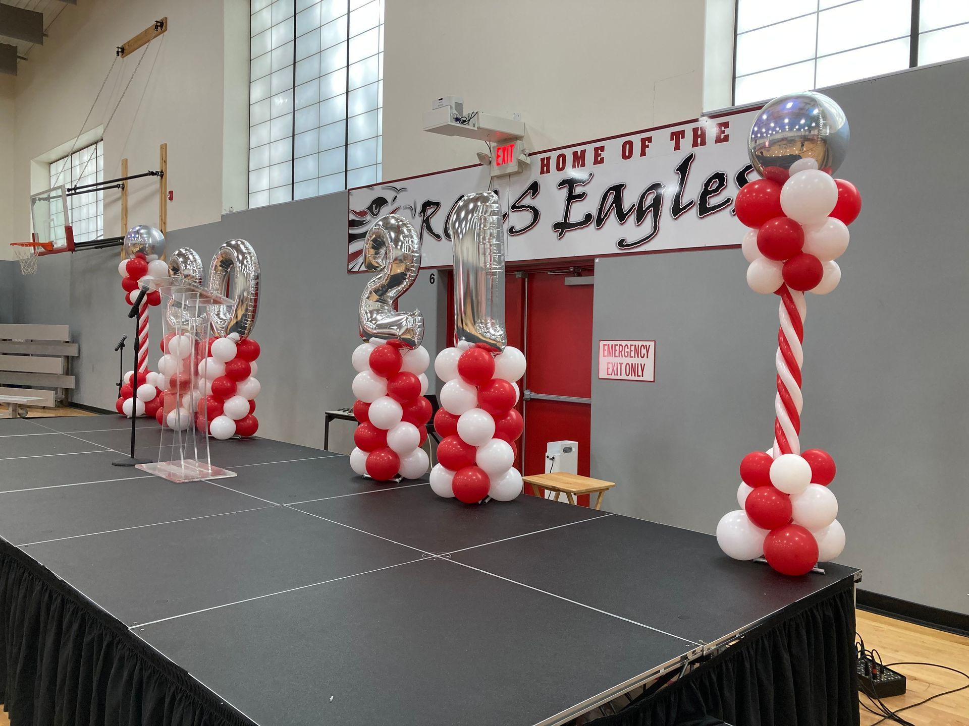 A stage decorated with red and white balloons and a sign that says time of the eagles