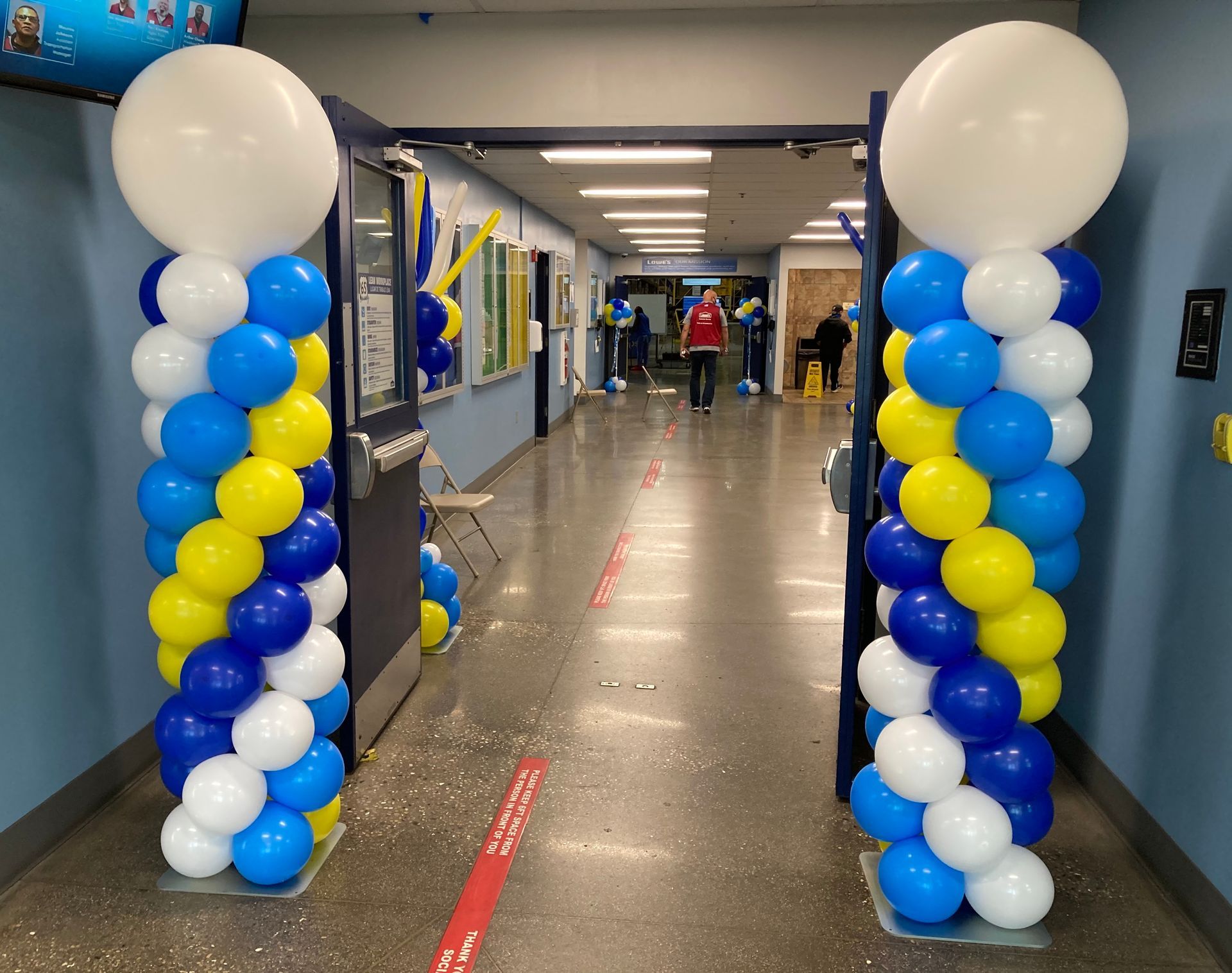 A hallway is decorated with blue and yellow balloons
