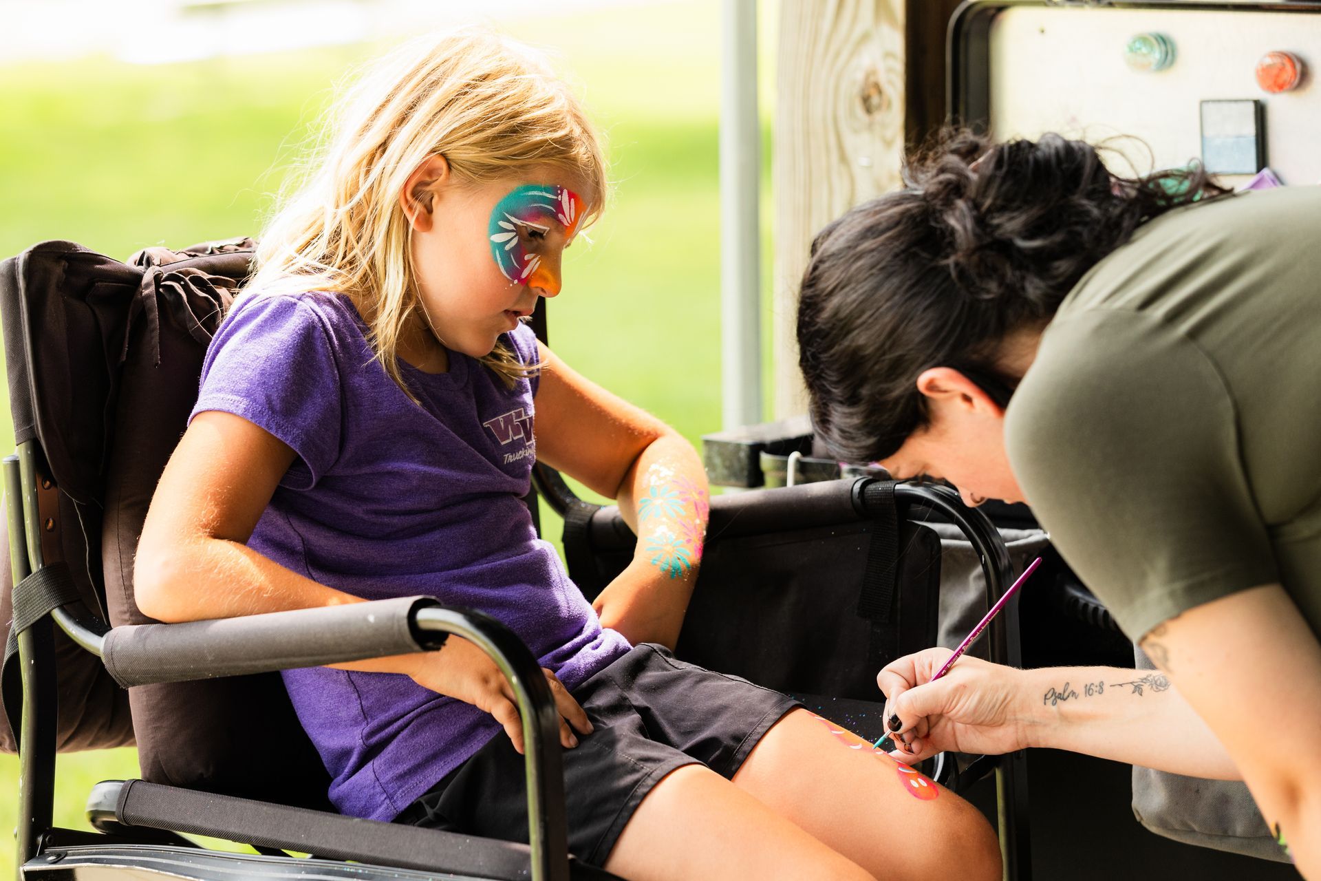 A little girl is sitting in a chair getting her face painted.