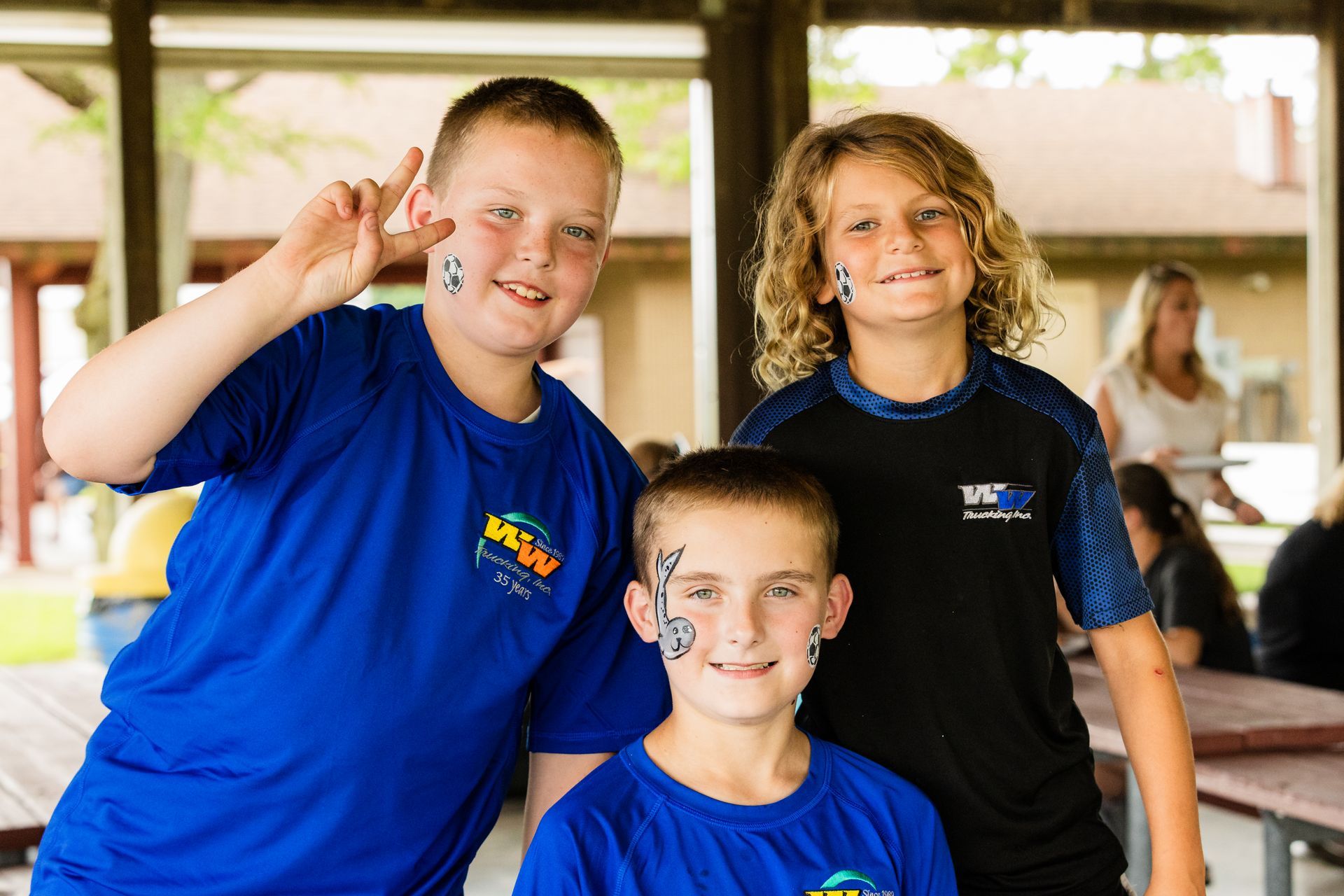 Three young boys wearing blue and black shirts are posing for a picture.