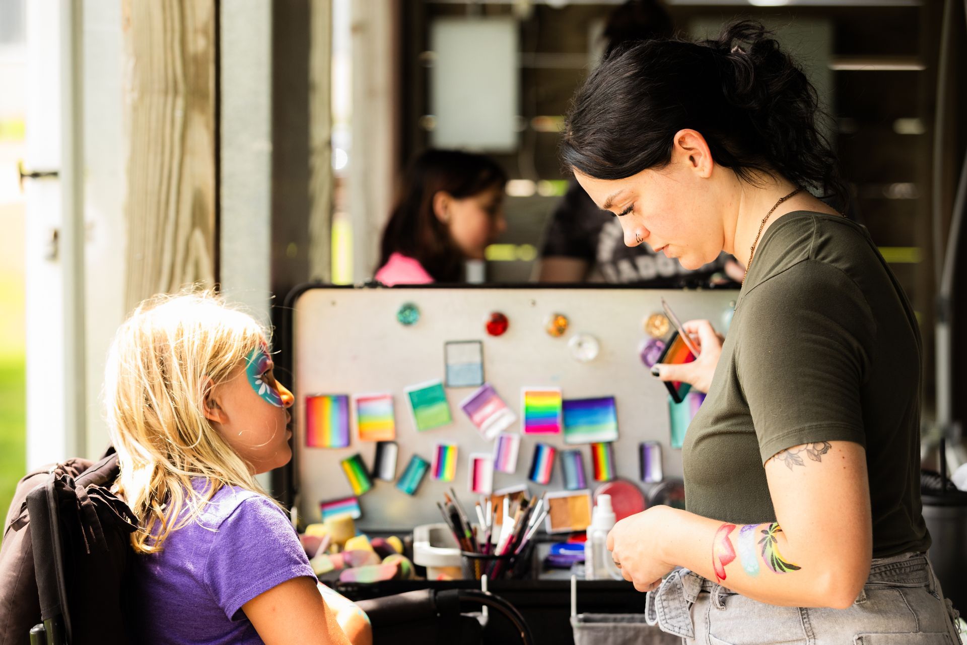 A woman is applying makeup to a little girl 's face.