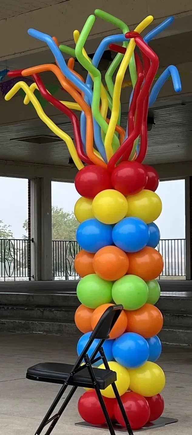 A chair is sitting in front of a colorful balloon column
