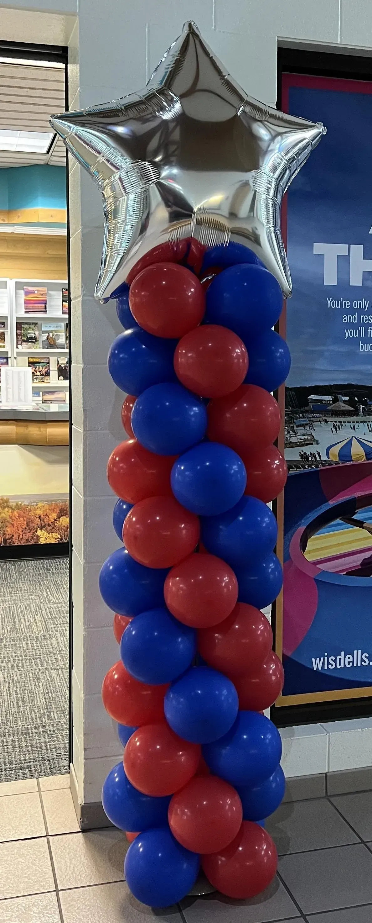 A balloon pillar with red , blue and silver balloons and a star balloon.