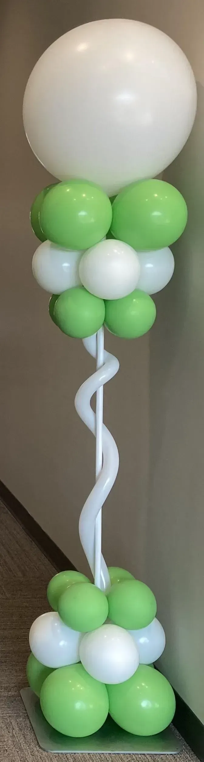 A green and white balloon tower with a white balloon in the middle.