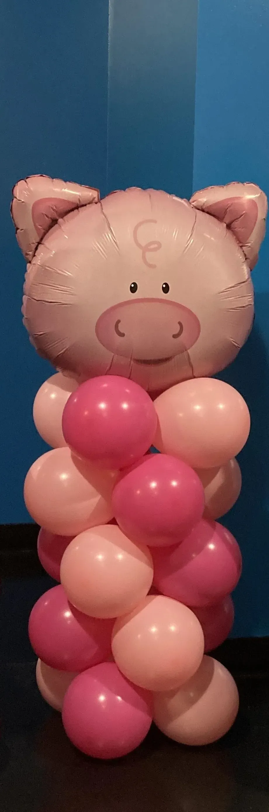 A balloon shaped like a pig is sitting on top of a pile of pink balloons.