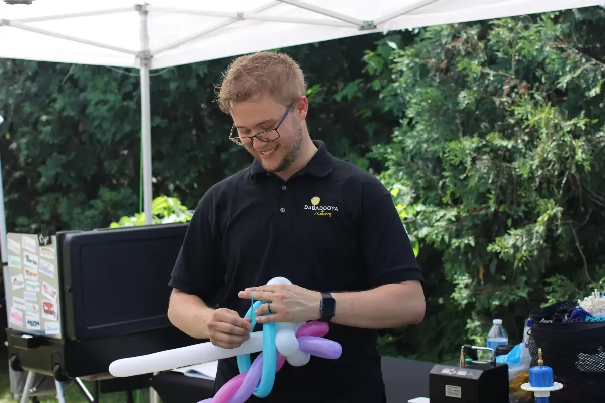 A man in a black shirt is holding balloons in his hands.