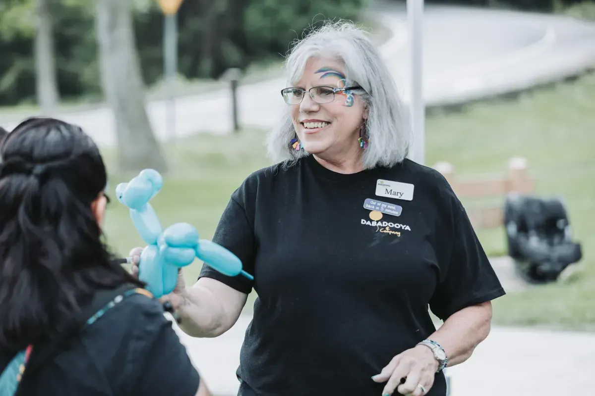 A woman in a black shirt is holding a blue balloon while talking to another woman.