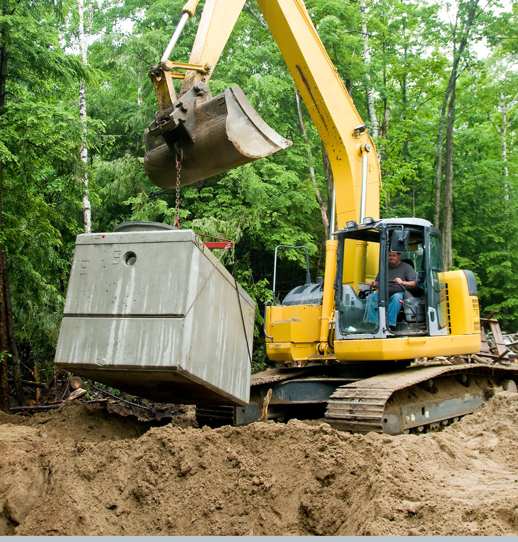 Construction site with wooden framing, blue dumpster, and orange forklift in muddy ground