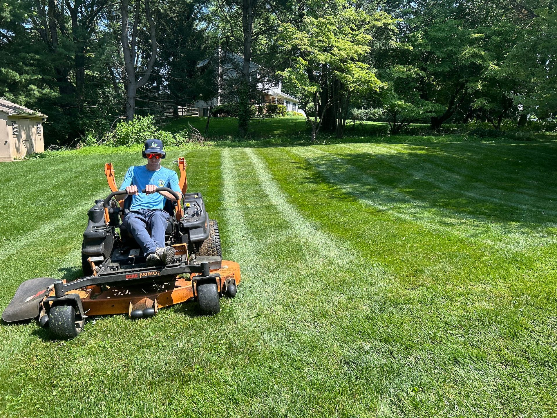 A man is riding a lawn mower on a lush green lawn.