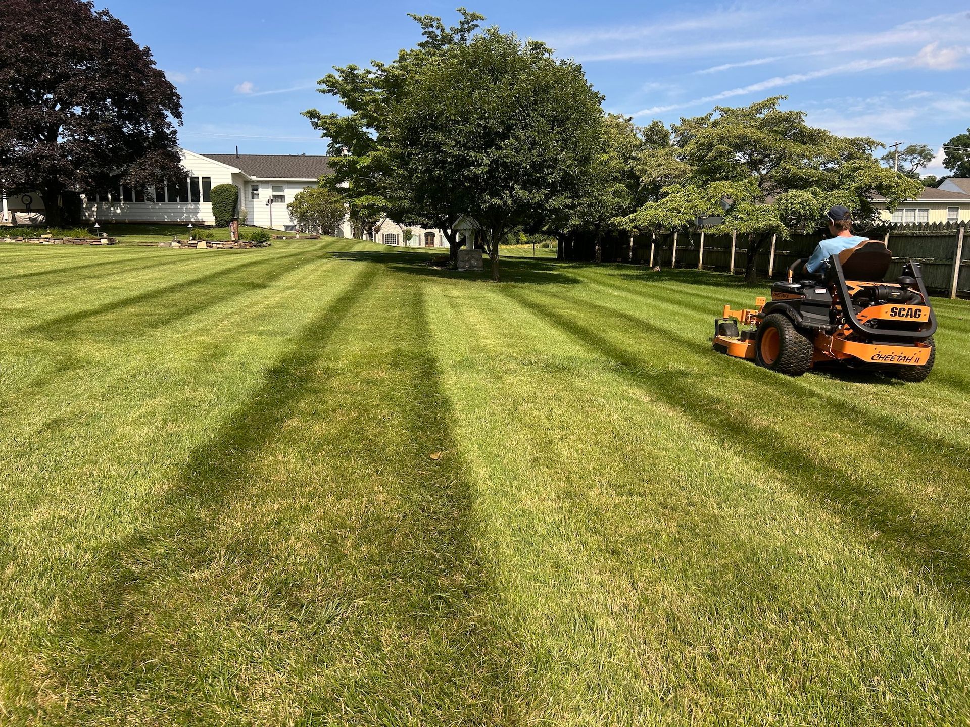 A man is riding a lawn mower on a lush green lawn.