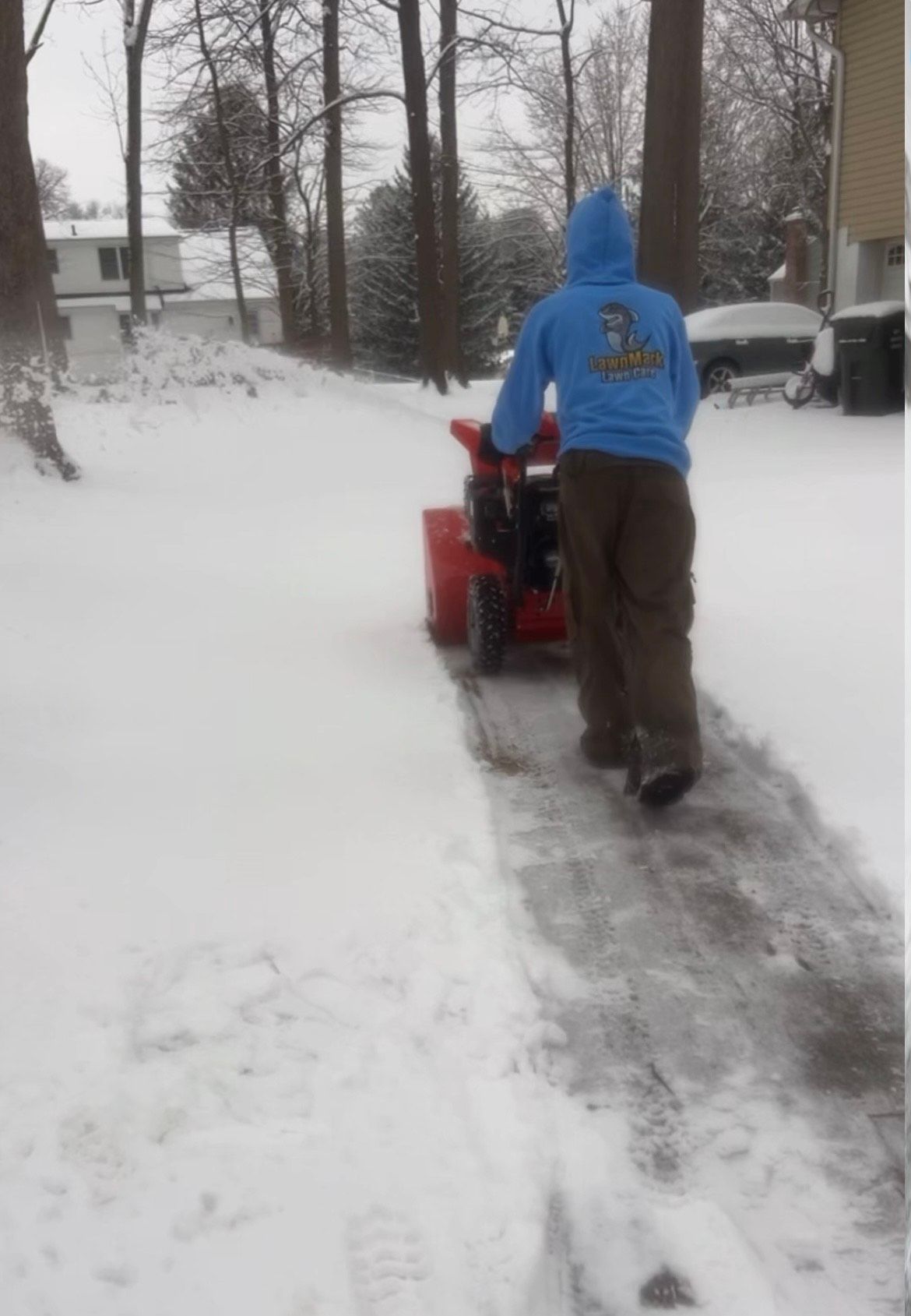A small red snow plow is sitting in the snow.