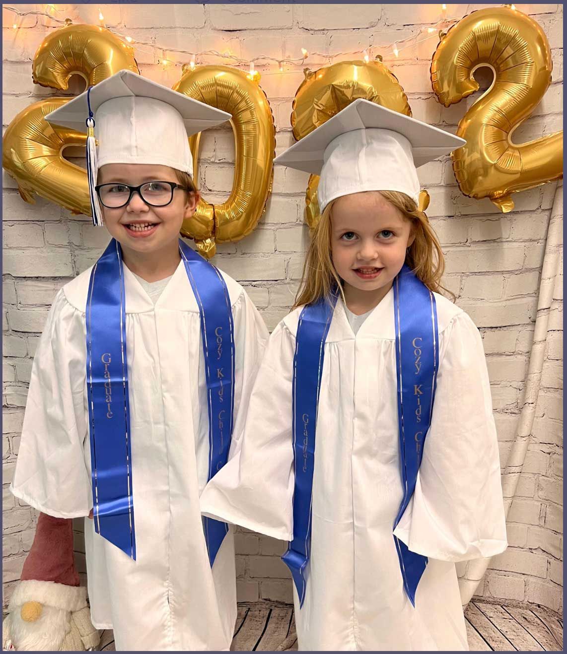 Two young girls wearing graduation caps and gowns are standing next to each other.