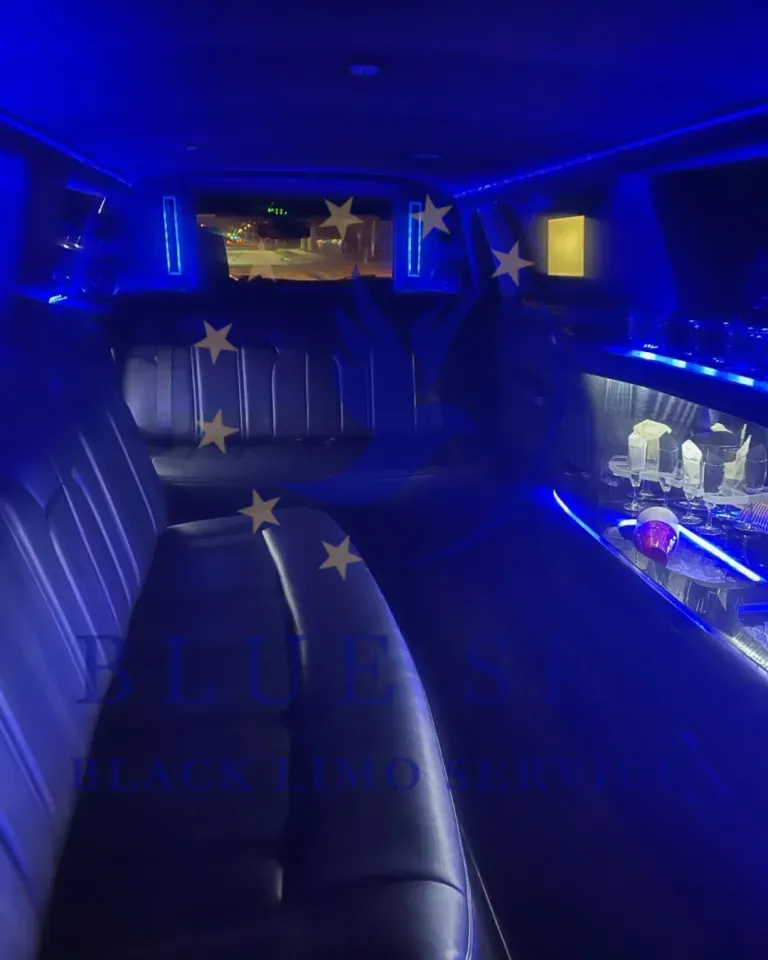 Blue-lit limousine interior with black leather seats, star decals, and a small illuminated bar area