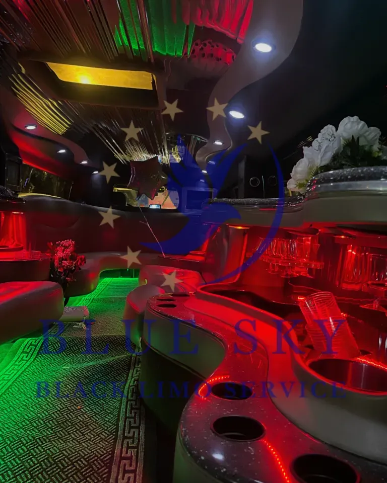 Interior of a white stretch limousine with leather bench seats and purple-green ambient lighting