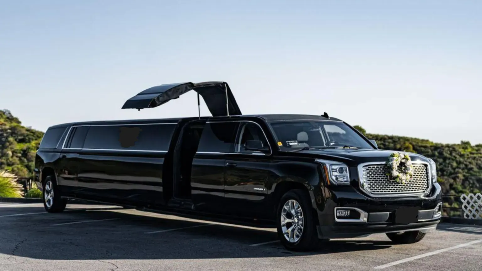 Black stretched limousine with open roof hatch parked on a road under a clear sky