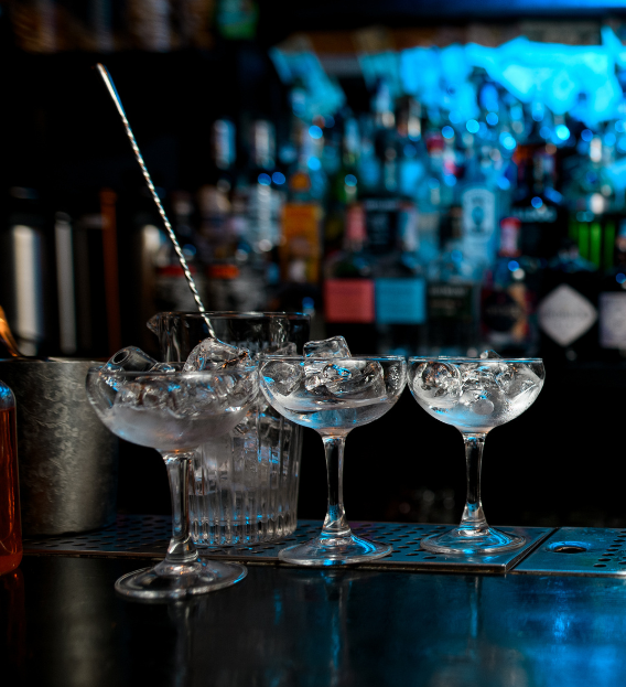 Three champagne glasses filled with ice are sitting on a bar.