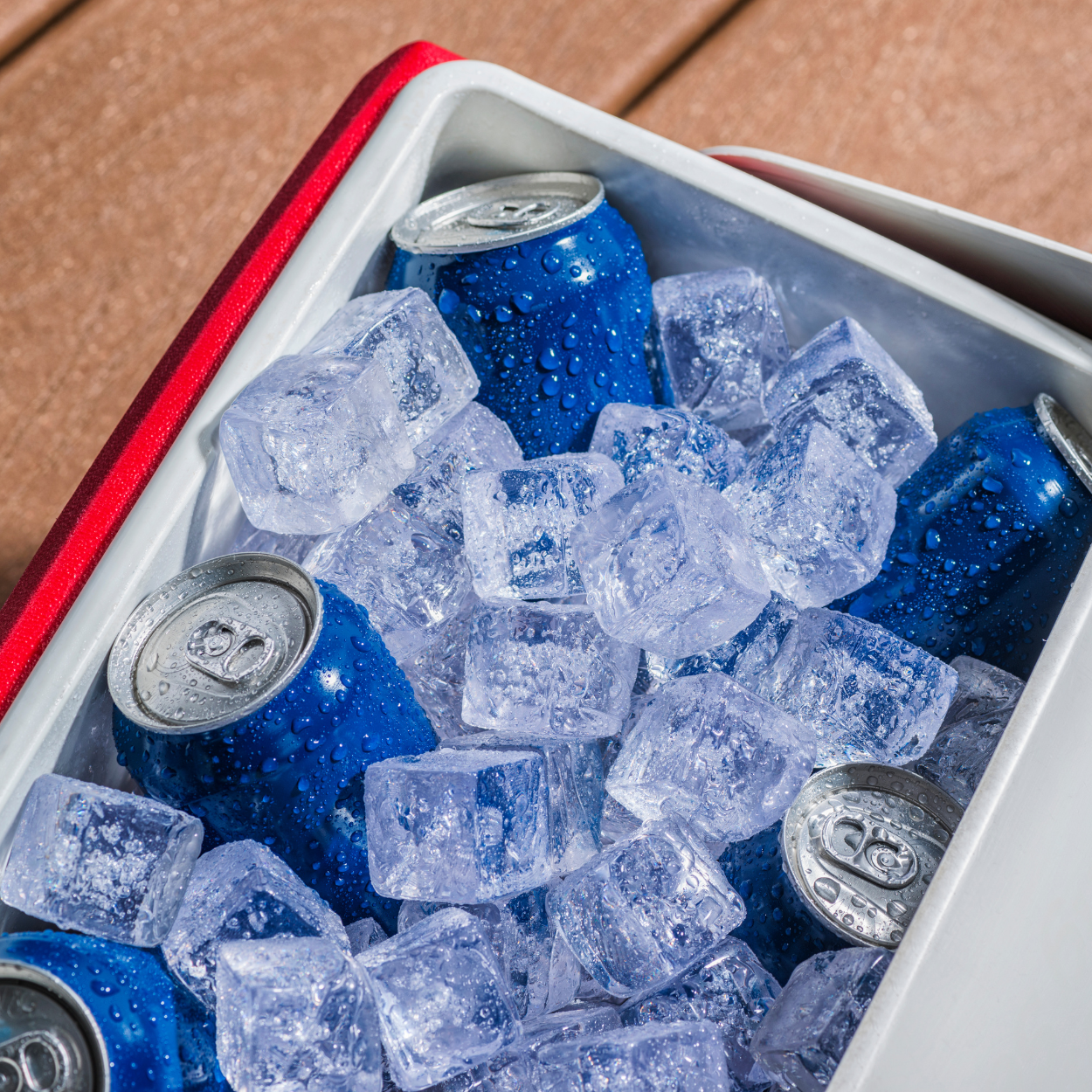 A cooler filled with blue cans and ice cubes.