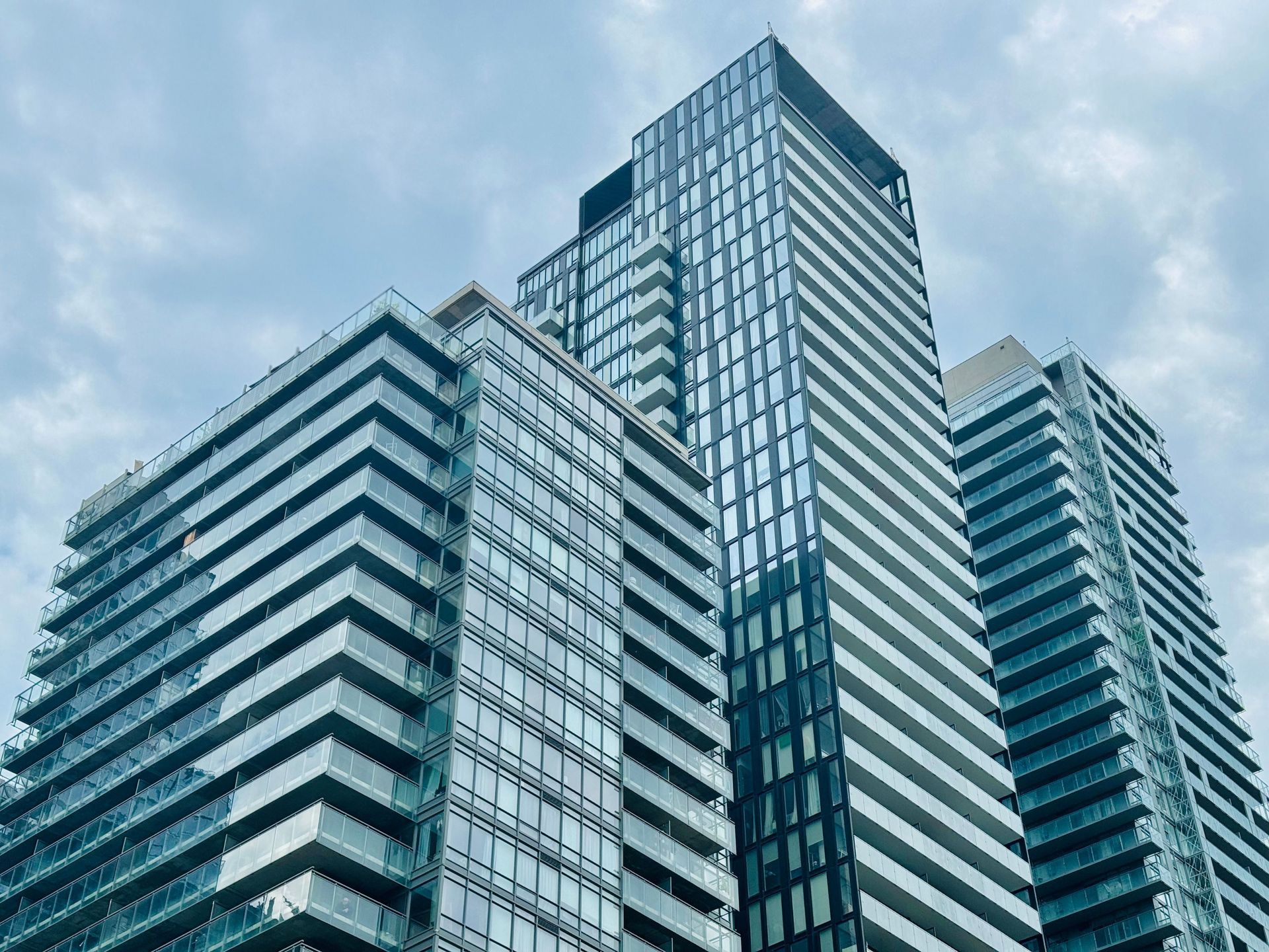 Modern glass skyscrapers against a cloudy blue sky