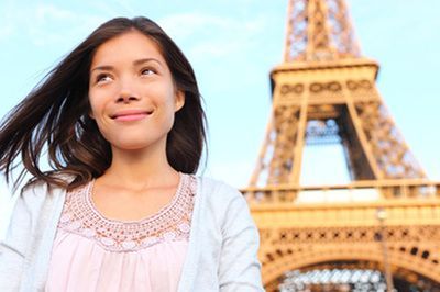 A woman is standing in front of the eiffel tower in paris.