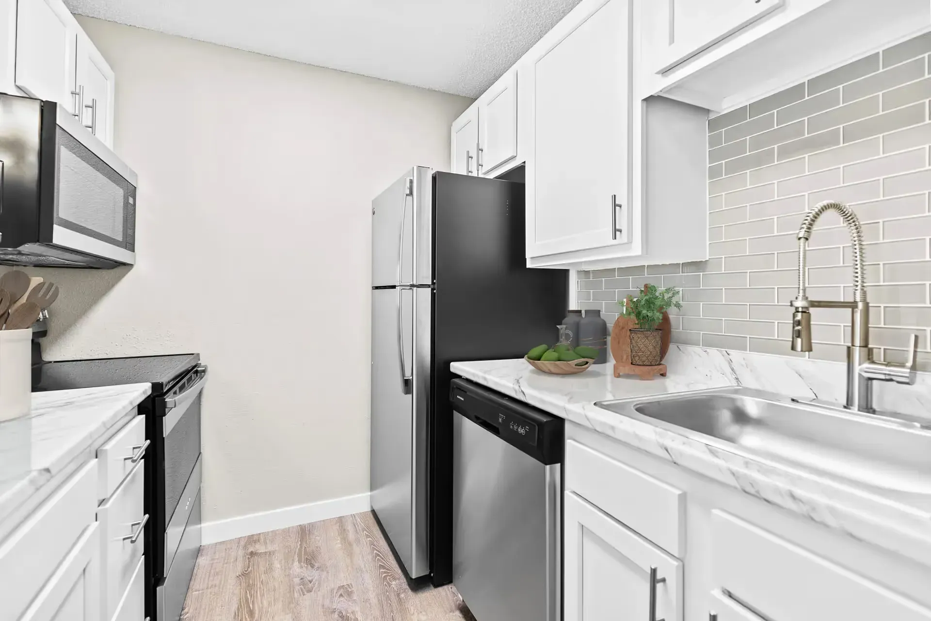 Modern galley kitchen with white cabinets, stainless steel appliances, and marble countertops at Avec Greeley.