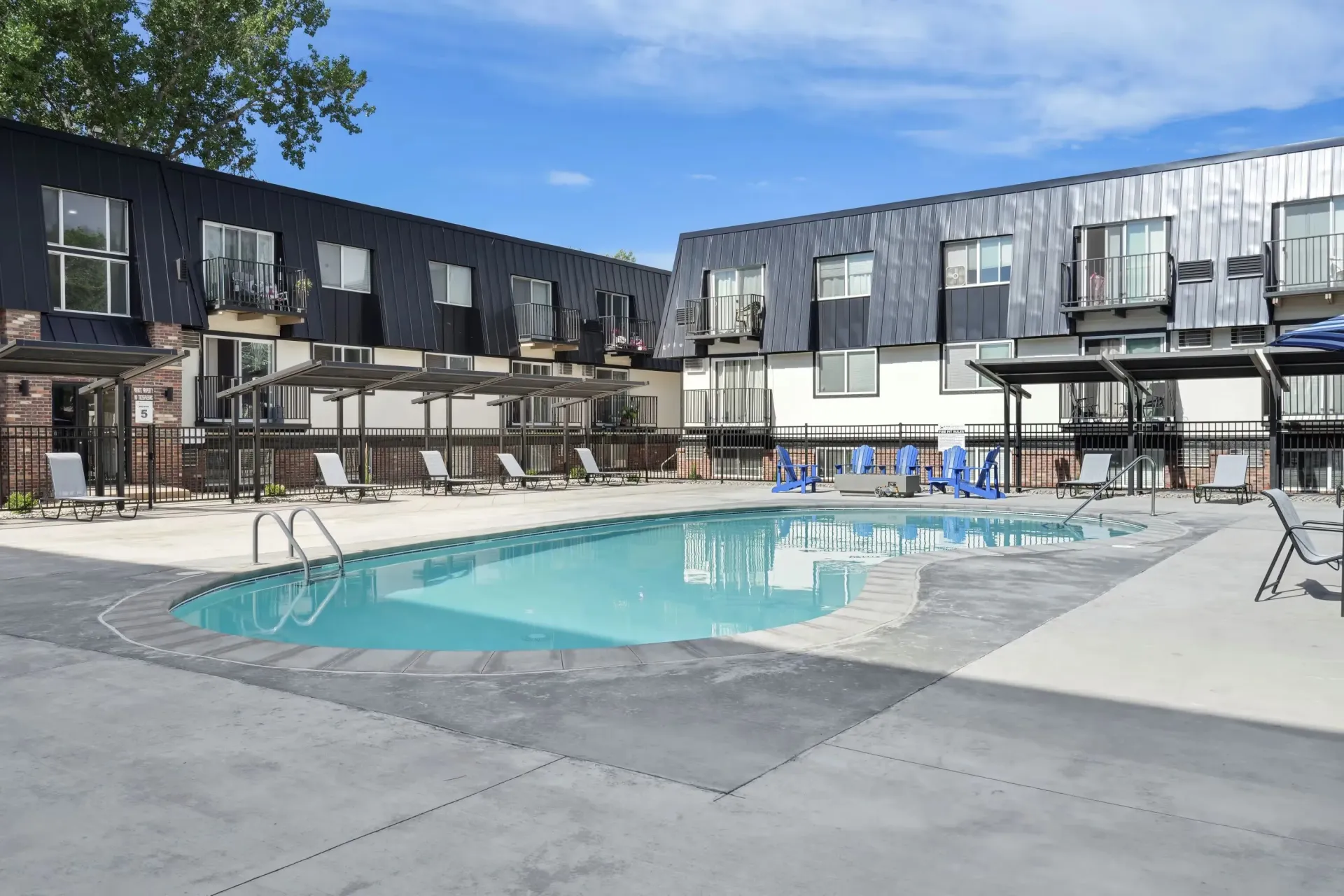 Outdoor pool area with lounge chairs and a modern apartment building in the background at Avec Greeley.